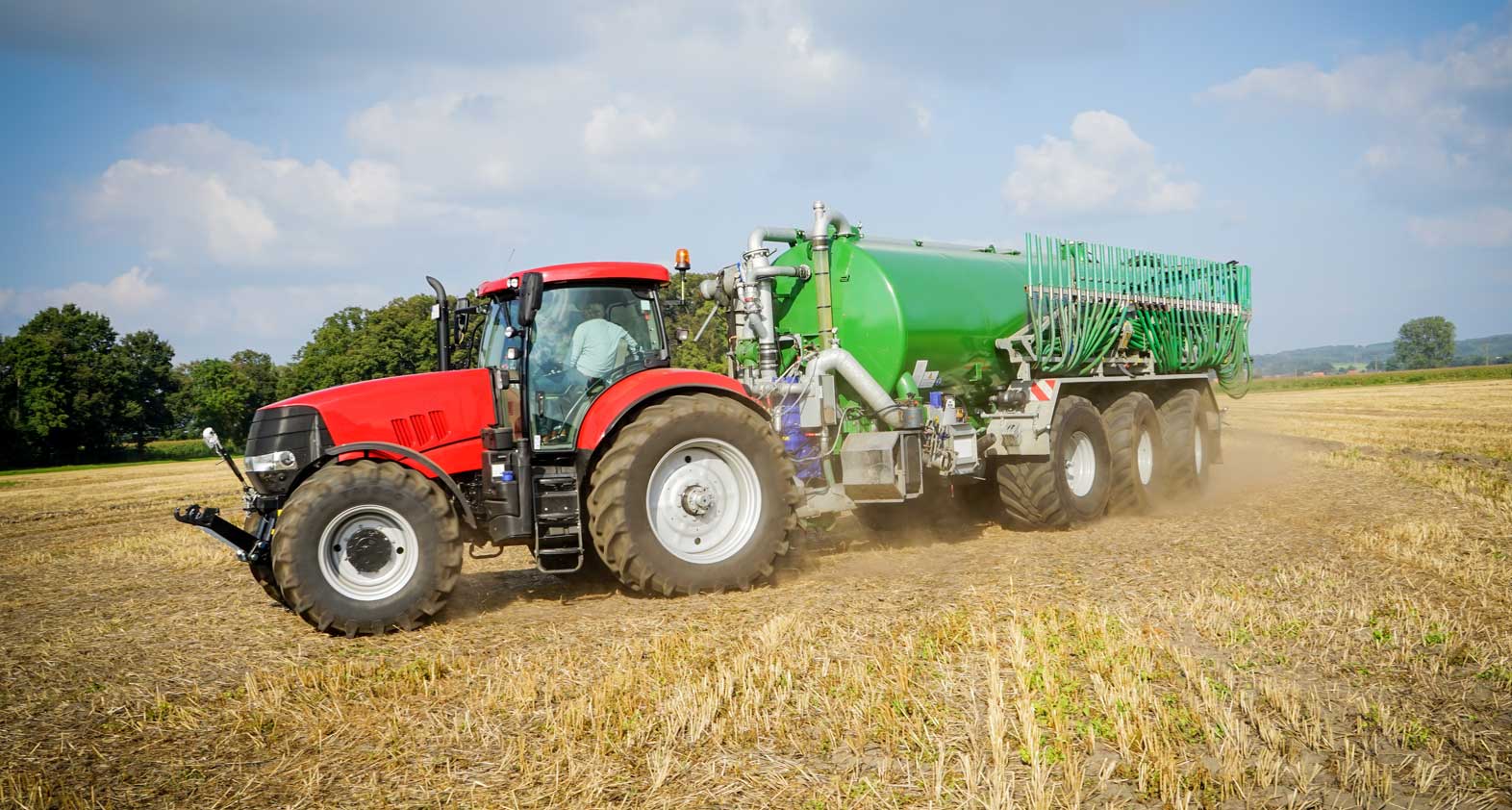 A tractor with a trailer fertilizing a harvested field
