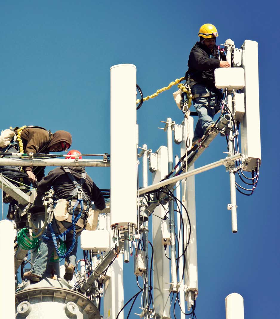 Three technicians performing maintenance work on a radio tower