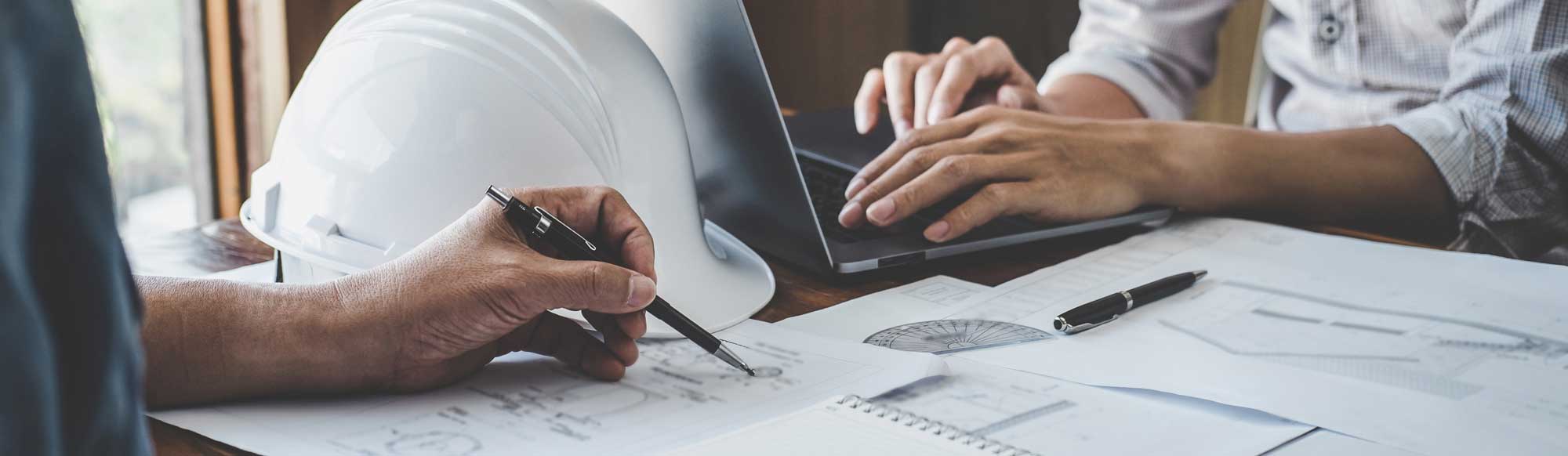 Project planning with blueprints and a laptop at the desk