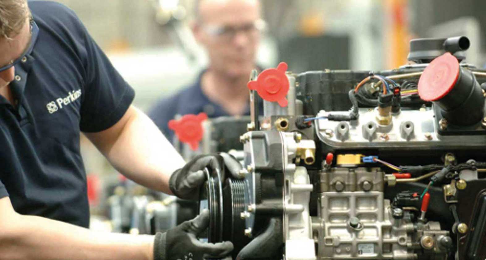 Deux monteurs en train d'assembler un moteur diesel de remplacement