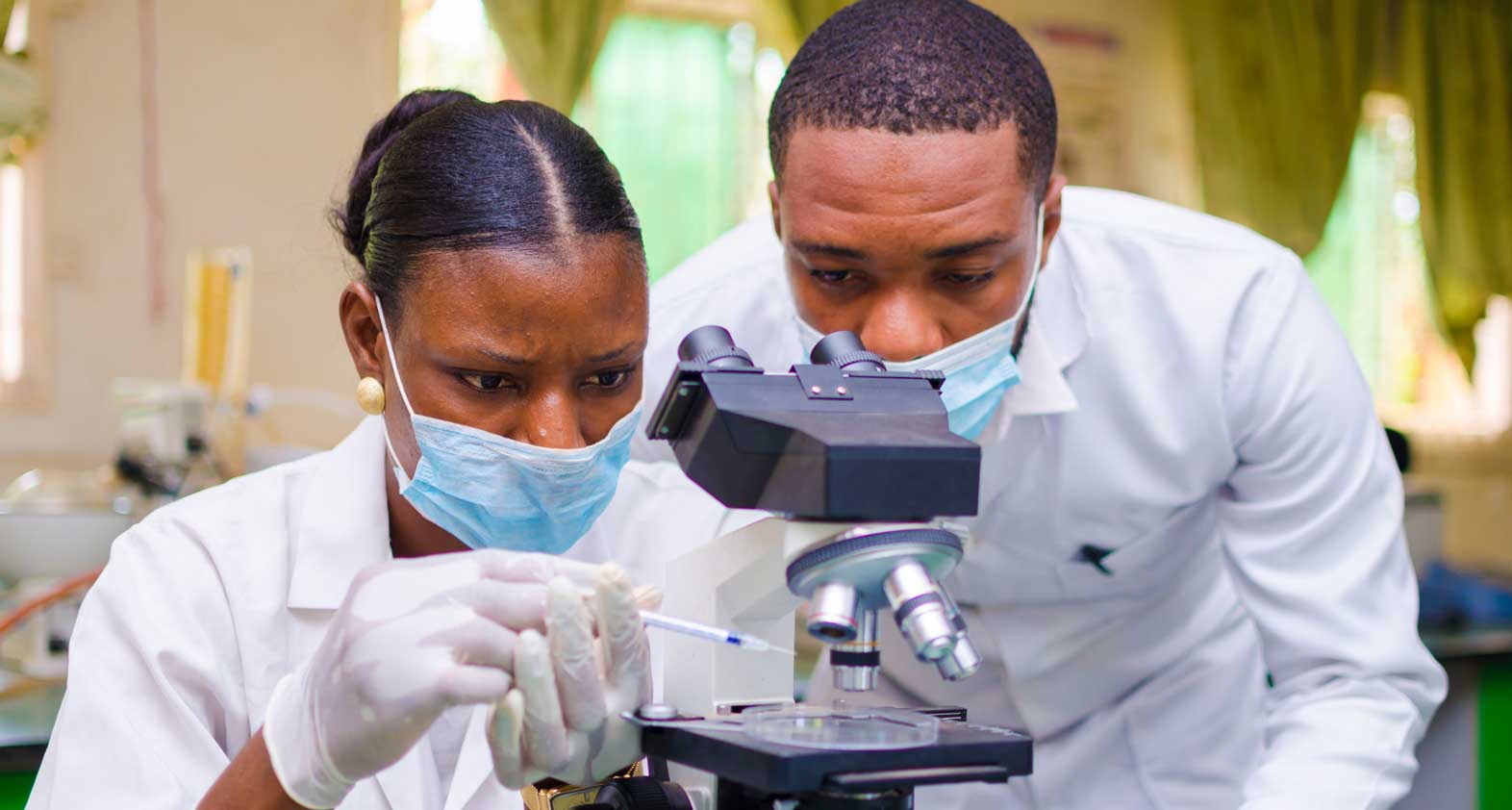 Two people at a microscope conducting water analysis in a laboratory